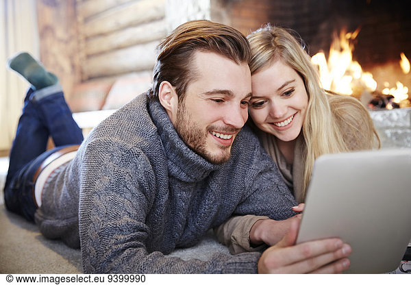 Couple using digital tablet by fireplace together