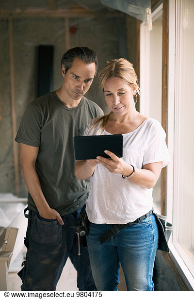 Couple using digital tablet in house being renovated
