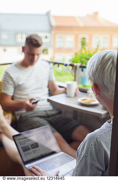 Couple using mobile devices on balcony
