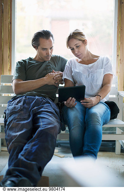 Couple using tablet computer in house being renovated