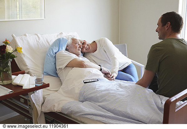 Couple visiting senior man in hospital