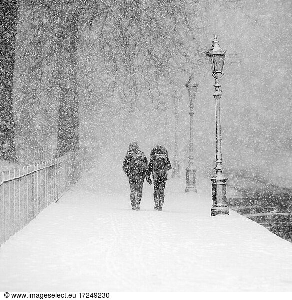 Couple walking together in snow-covered park during heavy snowfall