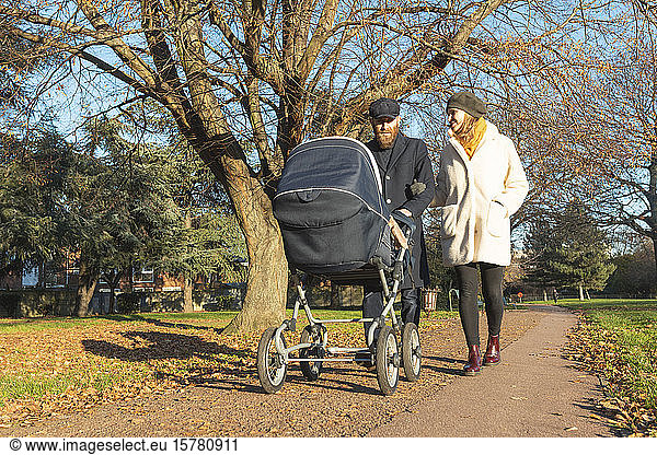 Couple walking with pushchair at park