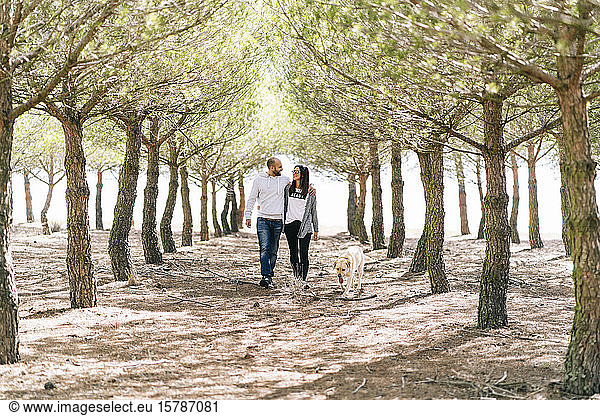 Couple walking with their dog in a park