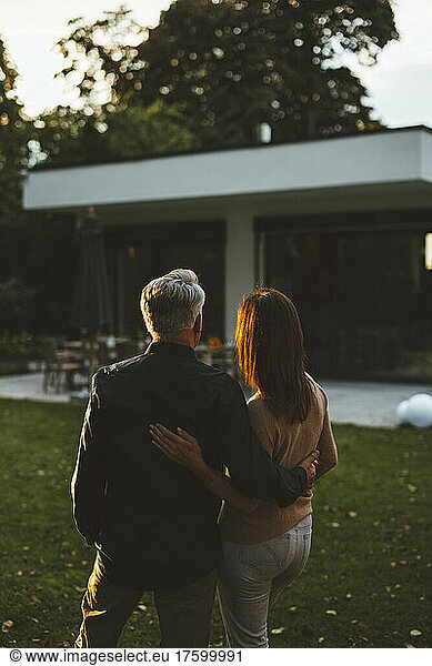 Couple with arms around standing at backyard on sunset