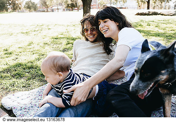 Couple with baby on picnic blanket in park
