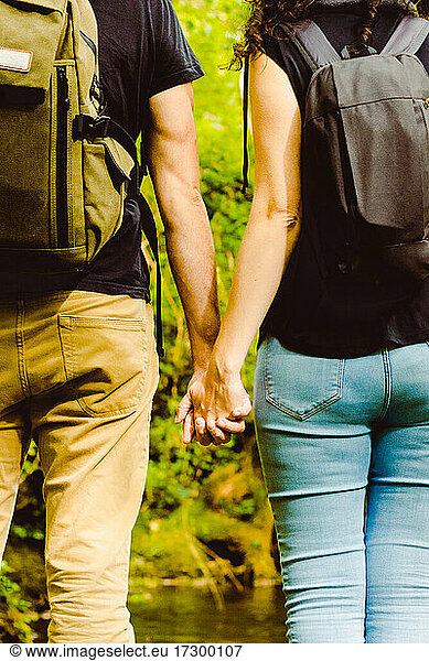 Couple with backpack in forest holding hands