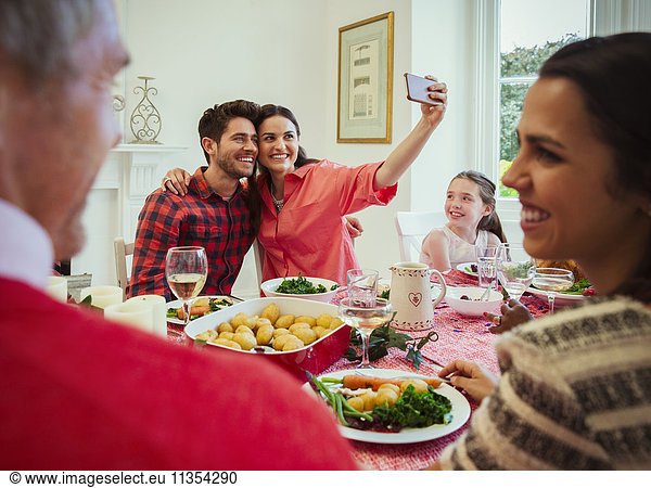Couple with camera phone taking selfie at Christmas dinner table