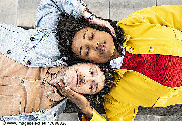 Couple with eyes closed lying together on footpath