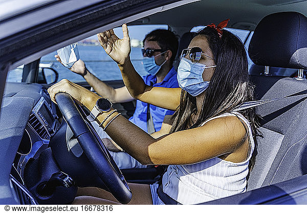 Couple with facemask arguing while she is driving a car in a dangerous