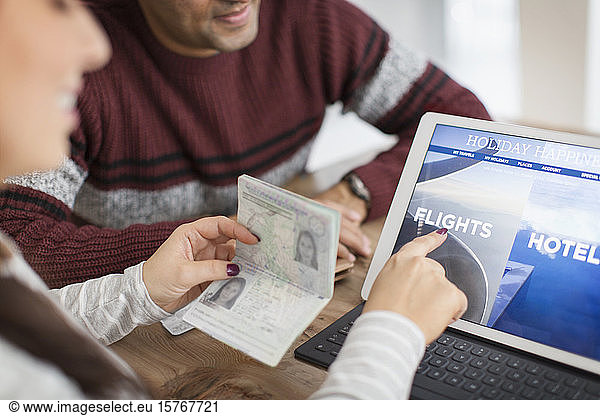 Couple with passport planning vacation at digital tablet