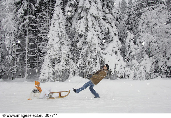 Couple with sledge having fun in snow