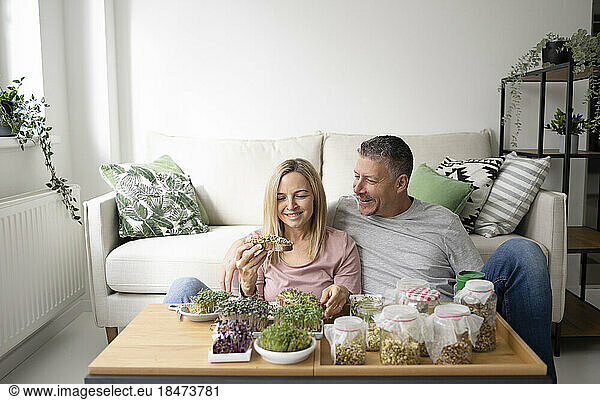 Couple with sprouts on toasted bread sitting at home