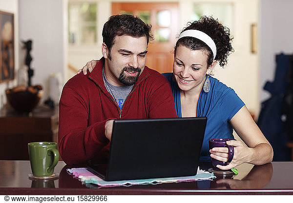 Couple work on laptop computer at home