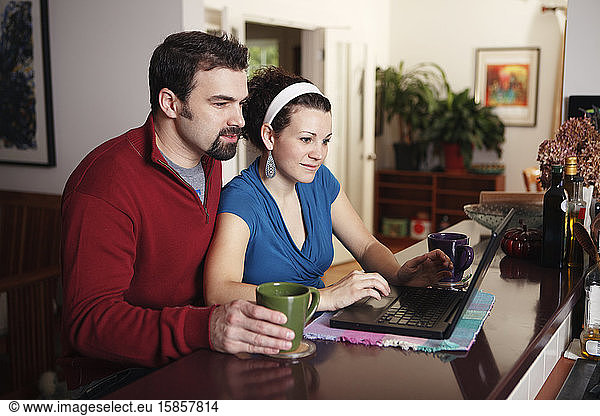 Couple work on laptop computer at home