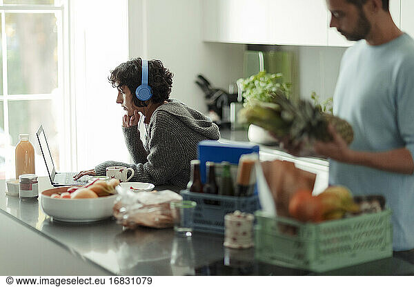 Couple working from home and unloading groceries in kitchen