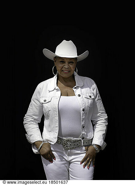 Cowgirl dressed in white against black backdrop