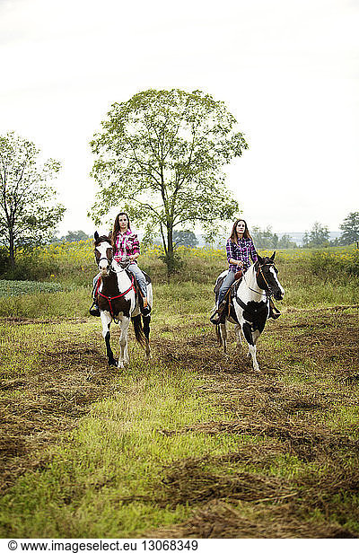 Cowgirls sitting on horses against sky
