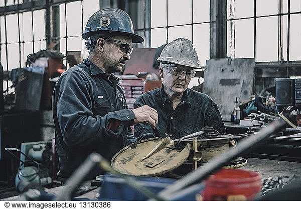 Coworkers working at table in metal industry