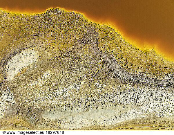 Cracked earth at the bank of the Rio Tinto (Red river) with its deep reddish hue due to oxidised iron minerals in its water. Aerial view. Drone shot. Huelva province  Andalusia  Spain.