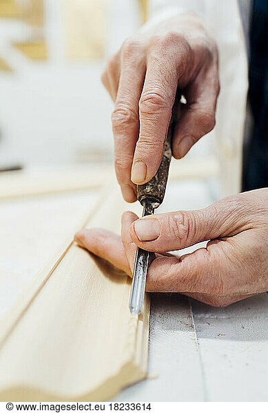 Craftsman carving wooden frame in workshop