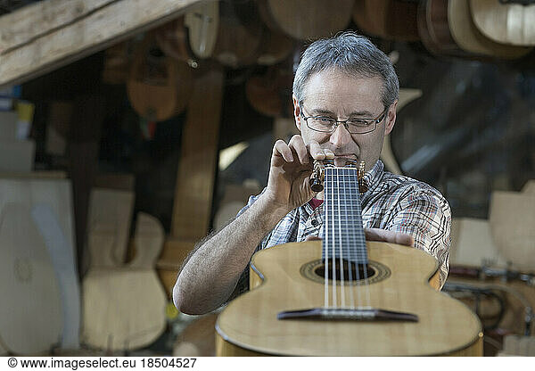 Craftsman examining guitar at workshop