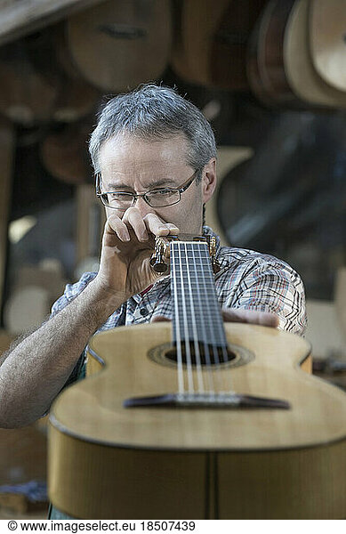Craftsman examining guitar at workshop