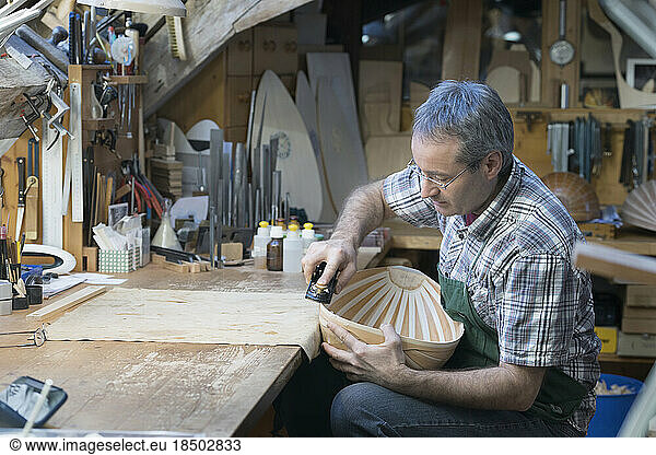 Craftsman manufacturing lute at workshop