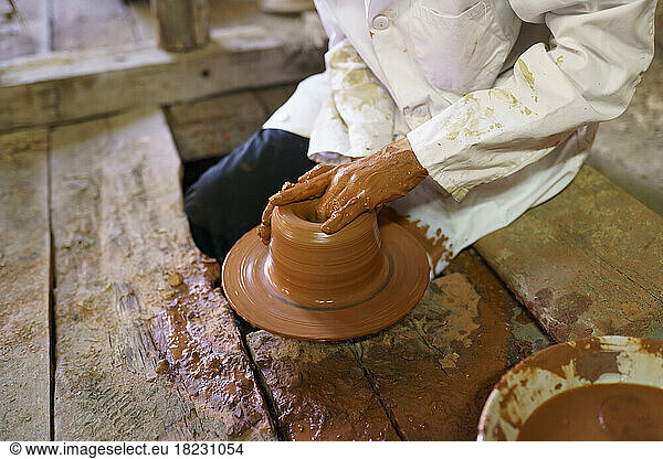 Craftsman molding clay on pottery wheel in factory