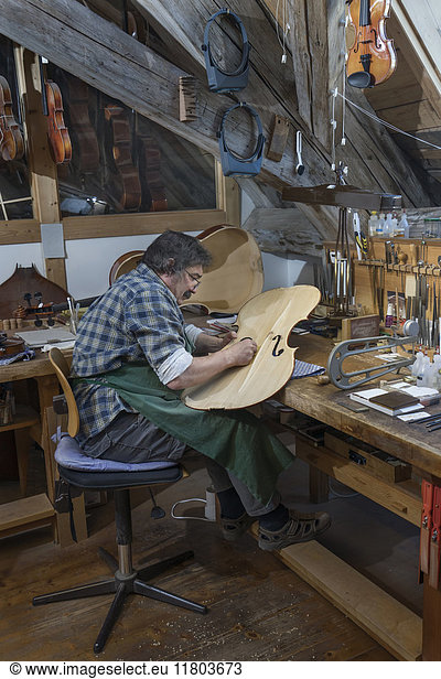 Craftsman working on violin in workshop