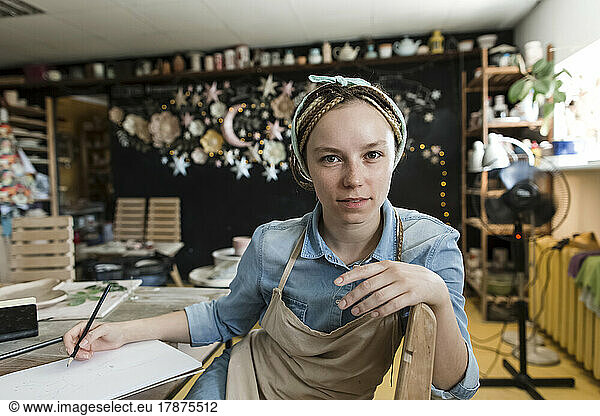 Craftsperson holding pencil at workbench in art studio