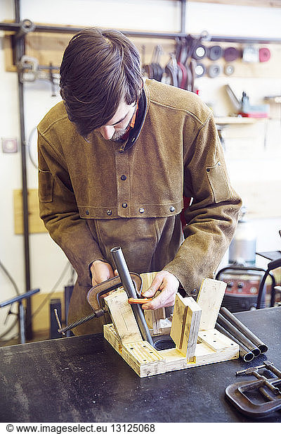 Craftsperson making wooden stool using clamp at workshop