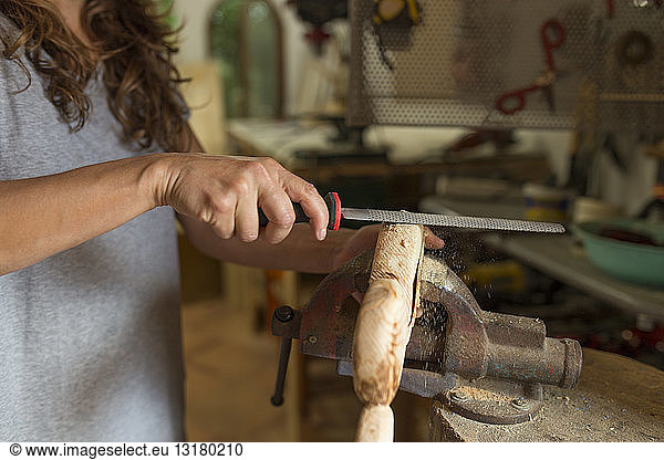 Craftswoman filing a piece of wood in her workshop