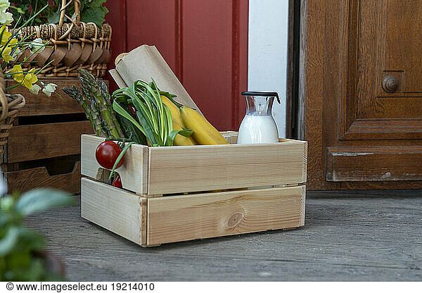 Crate of organic groceries near house door