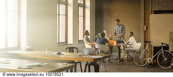 Creative businessman leading meeting at table in office