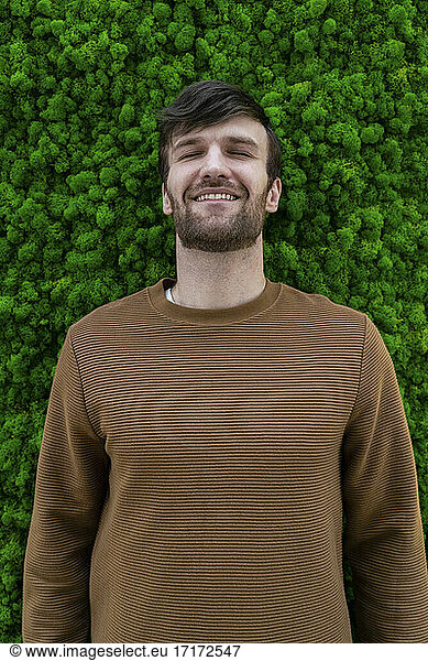 Creative businessman smiling while standing against green backdrop