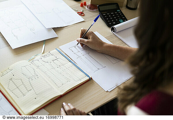 Creative female professional sketching design on paper at studio