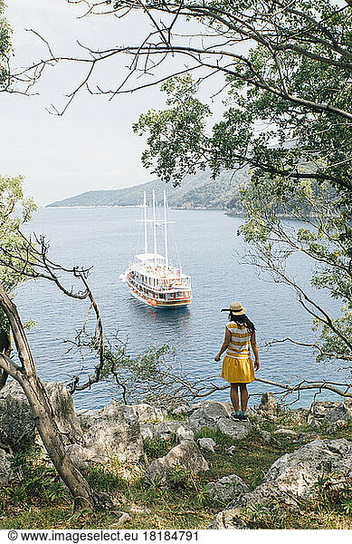 Croatia  Cres  woman standing at the coast looking at the sea with sailing ship