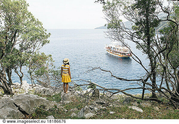 Croatia  Cres  woman standing at the coast looking at the sea with sailing ship