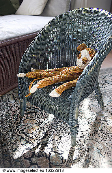 Crocheted toy monkey on wicker chair