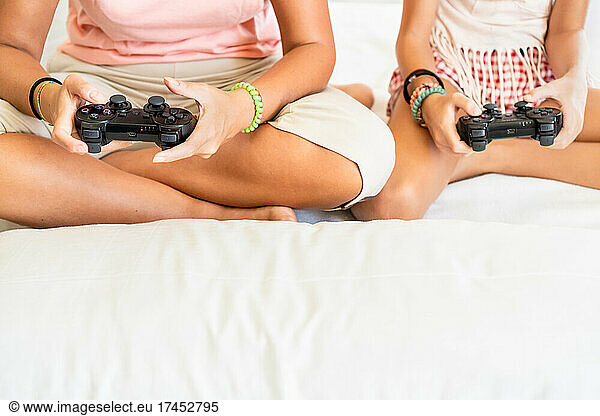Crop mother and daughter playing video games together sitting on floor