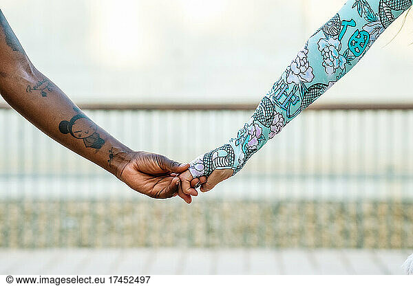 Crop multiracial girlfriends holding hands on street