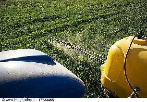 Crop sprayer spraying fertilizer on field on sunny day
