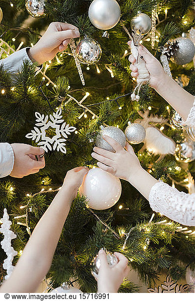 Crop view of children's hands decorating Christmas tree