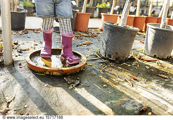 Crop view of little girl wearing Wellington Boots playing at pant nursery