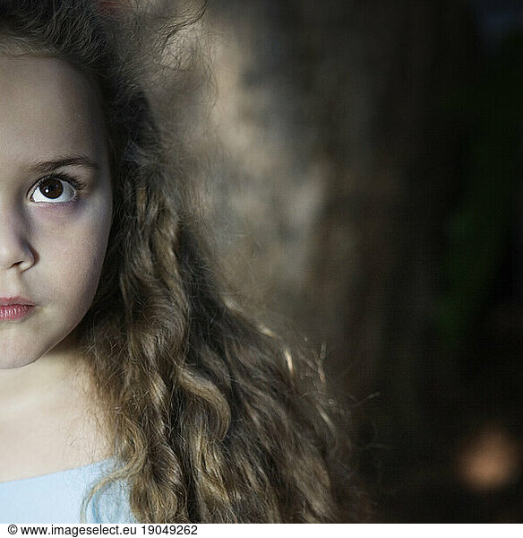 Cropped front view portrait of a young girl looking up.