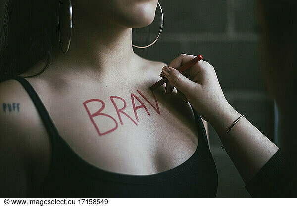 Cropped hand of woman writing on female activist's chest