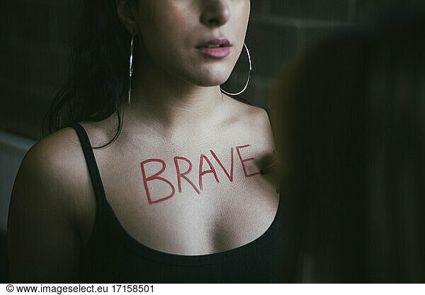 Cropped hand of woman writing on female protestor's chest