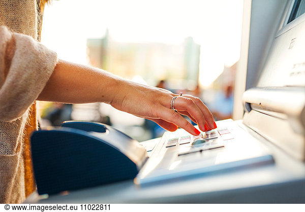 Cropped hand on woman using ticket machine at railroad station
