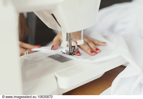 Cropped hands of fashion designer using sewing machine